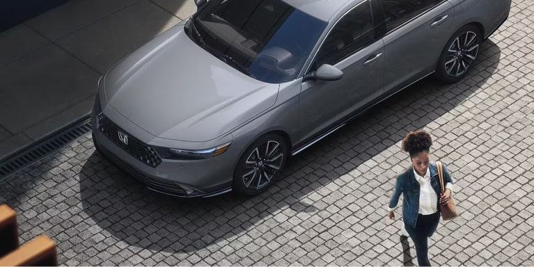 woman walking away from a gray honda accord hybrid on street
