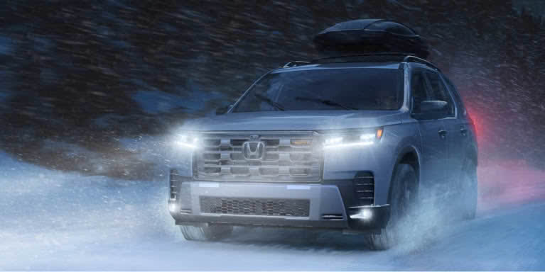 Front shot of a white Honda Pilot driving on a curved mountain road