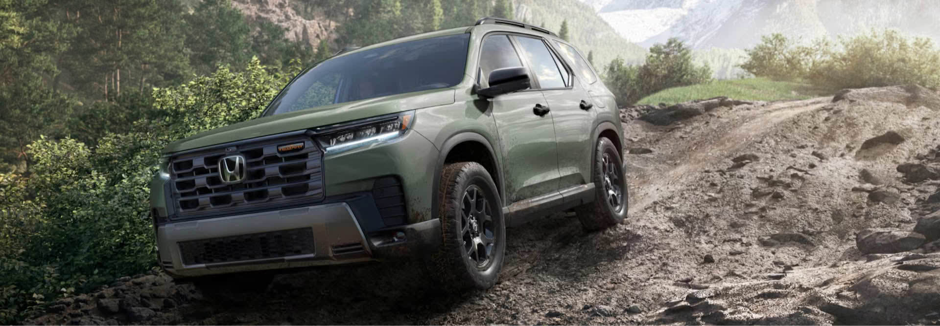 A green Honda Pilot driving out of a stream in the woods