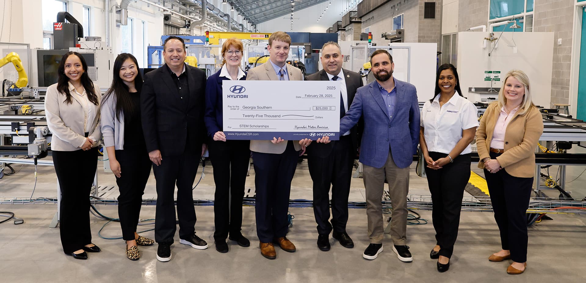 Hyundai representatives and Georgia Southern University staff posing in a technical lab with a ceremonial check for STEM scholarships.