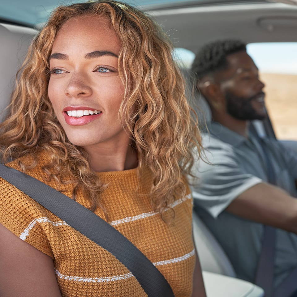 Passenger looking out window while driver sits behind wheel