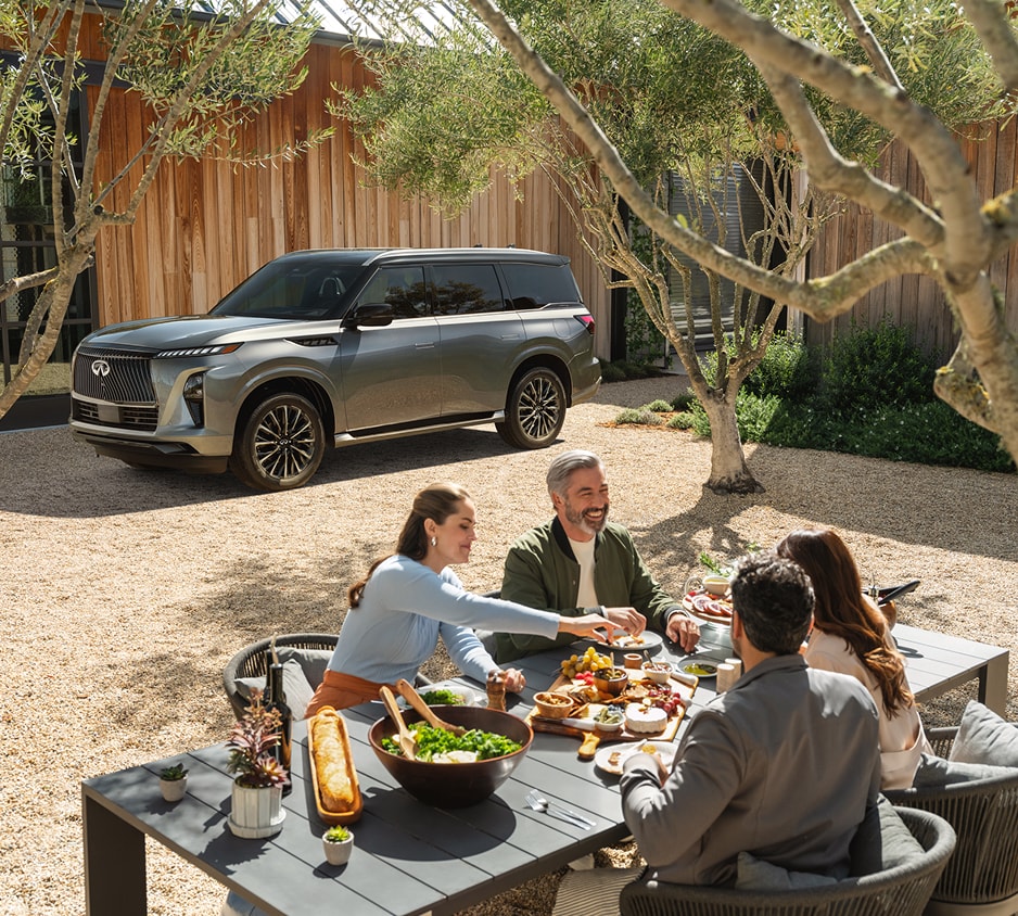 family eating at a picnic table with a QX80 in the background