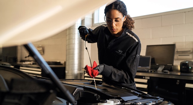 INFINITI maintenance technician checking a dipstick
