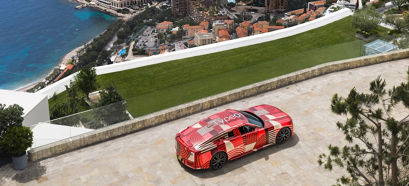 Jaguar Type 01 driving along a hillside road with the shore line beneath
