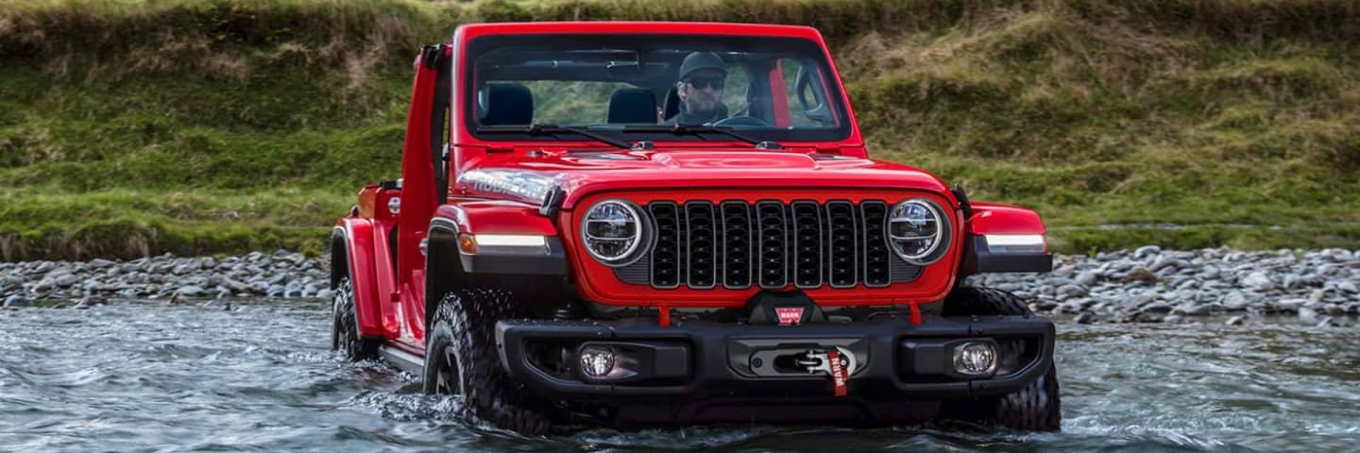Jeep Wrangler driving through a stream