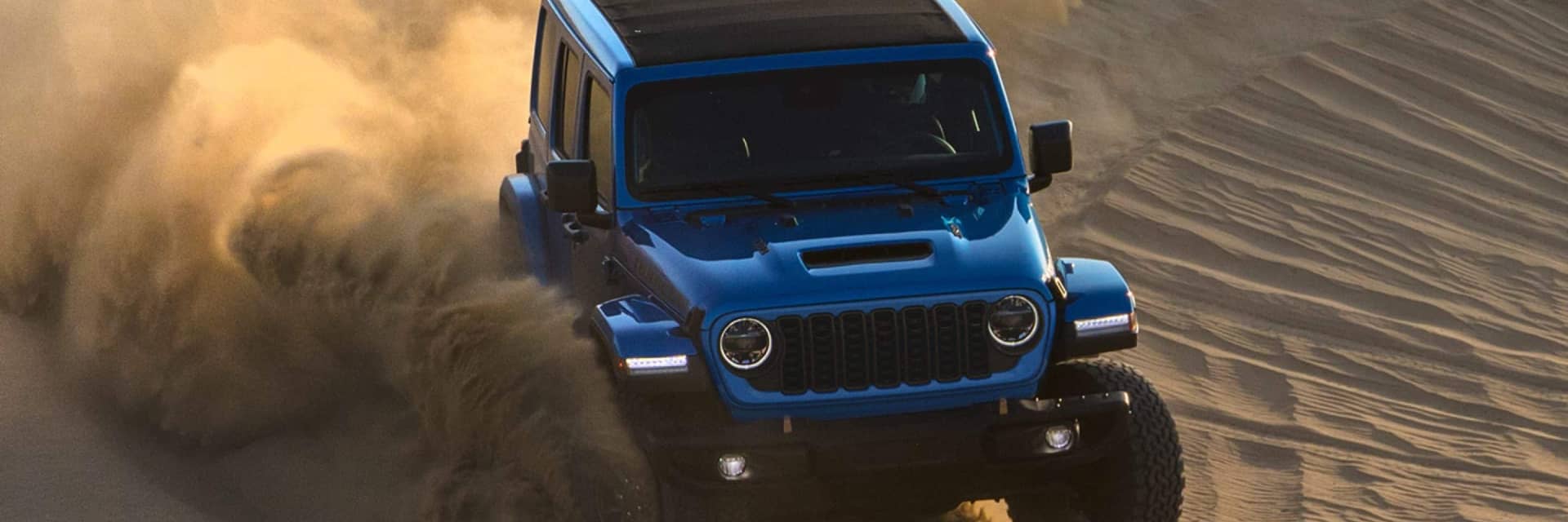Jeep Wrangler kicking up sand as it turns