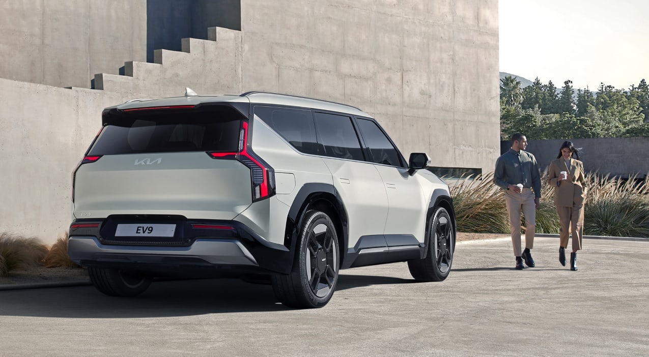 Back view of a Kia SUV with two people walking near it