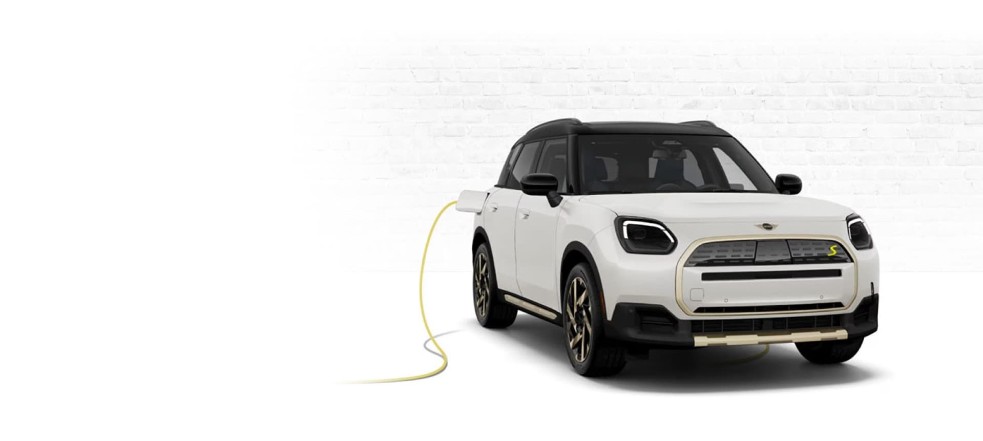 Angled view of a white MINI Countryman SE ALL4 parked with charging cord.