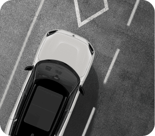Overhead view of a green MINI vehicle with white roof parked on a pavement surface with white lane lines on each side of the vehicle.