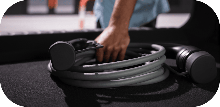 A person grabs an electric vehicle charger from their trunk.
