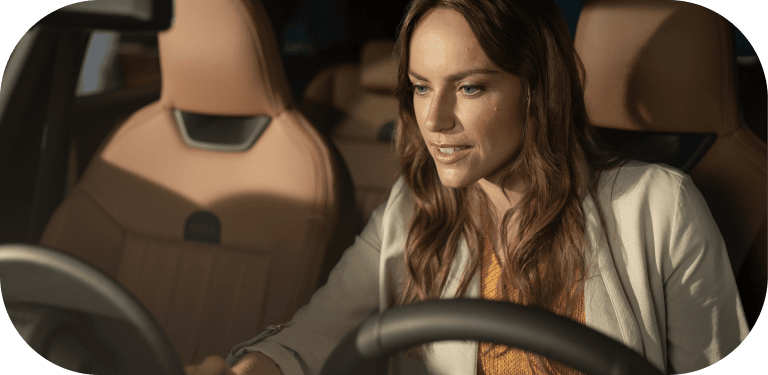 A woman looks down at the MINI OLED Display from the driver’s seat of her MINI.