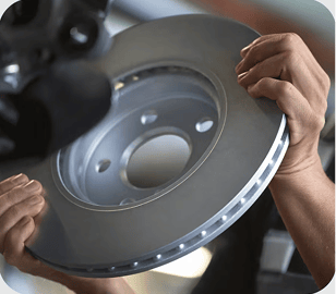 Closeup view of hands holding a circular piece of metal with the background blurred out.