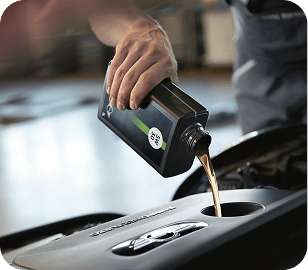 Closeup view of hand pouring motor oil into an engine with the background blurred out.