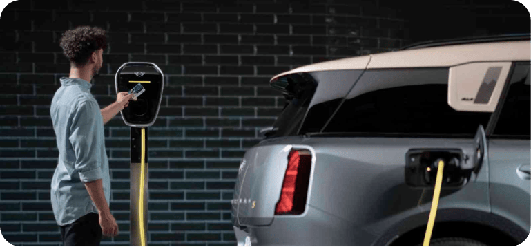 A man charges his MINI Countryman SE ALL4 using a MINI Wallbox