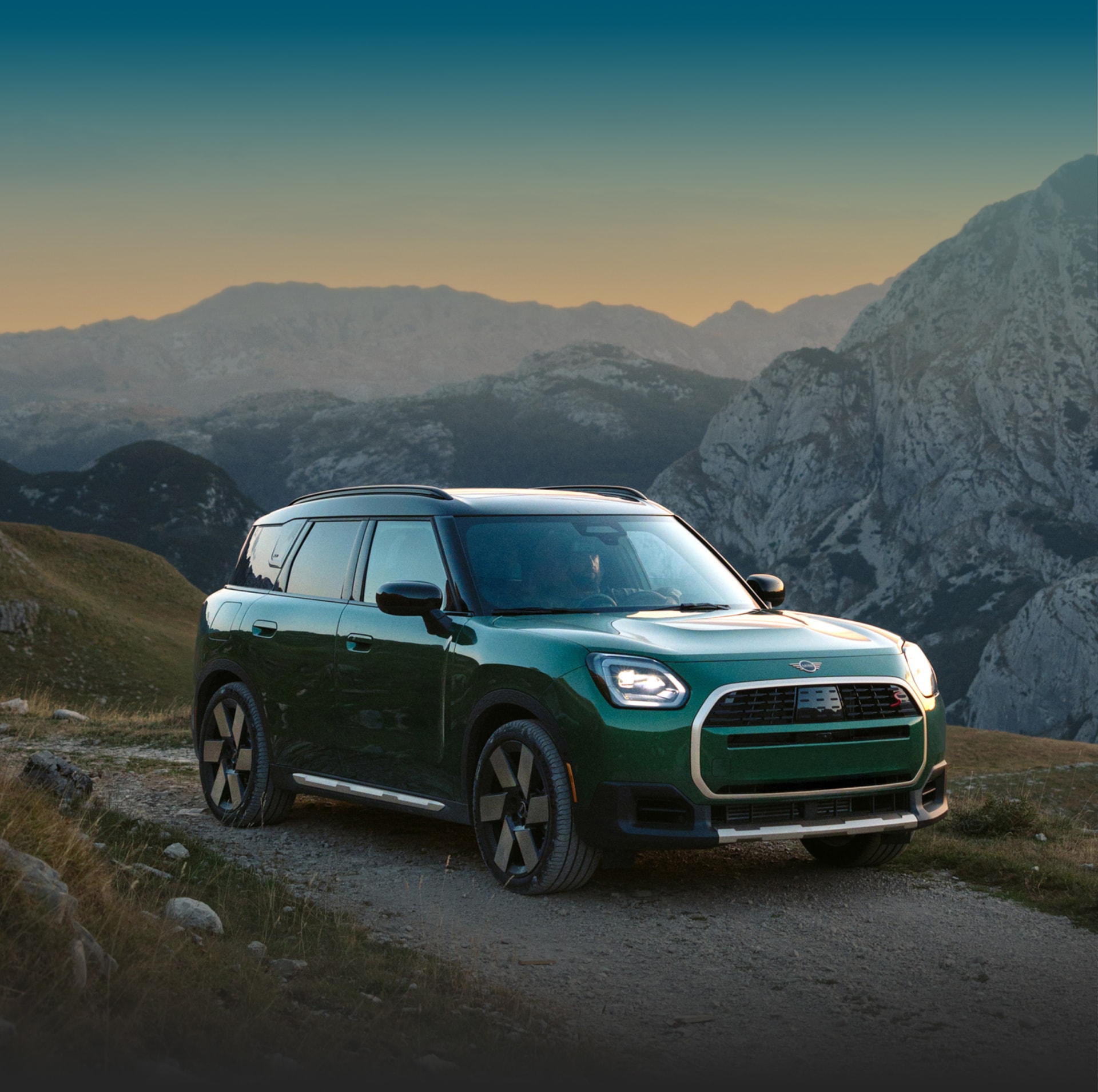 The MINI Countryman S ALL4 drives on rugged terrain with mountains in the background. 
