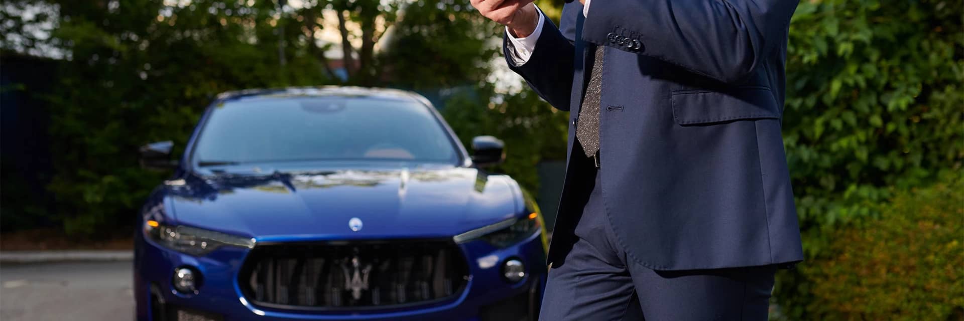 A man in a suit standing in front of a blue 2023 Maserati Quattroporte