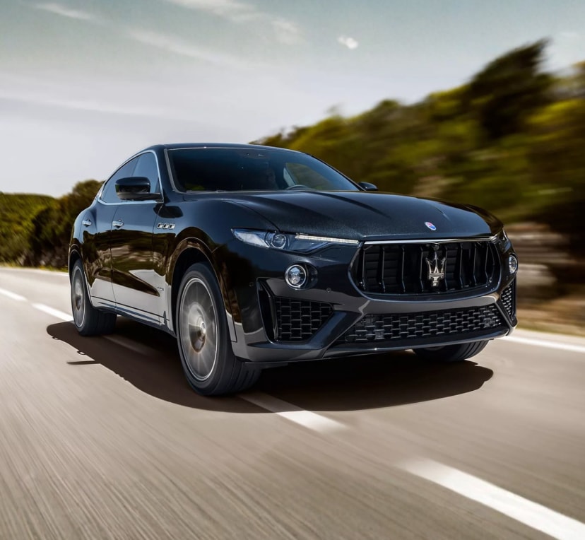 Maserati SUV driving on a highway with a hilly motion-blurred background