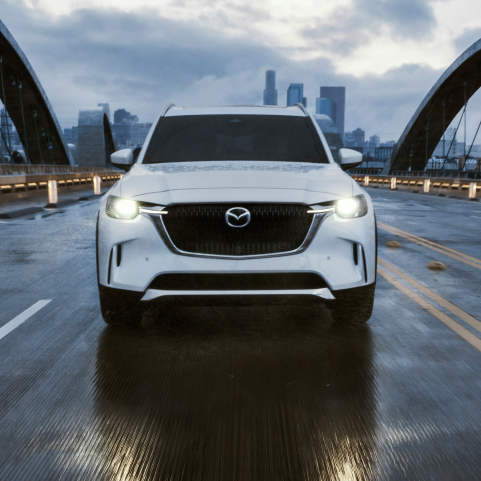 Mazda CX-90 PHEV driving down street front view. 