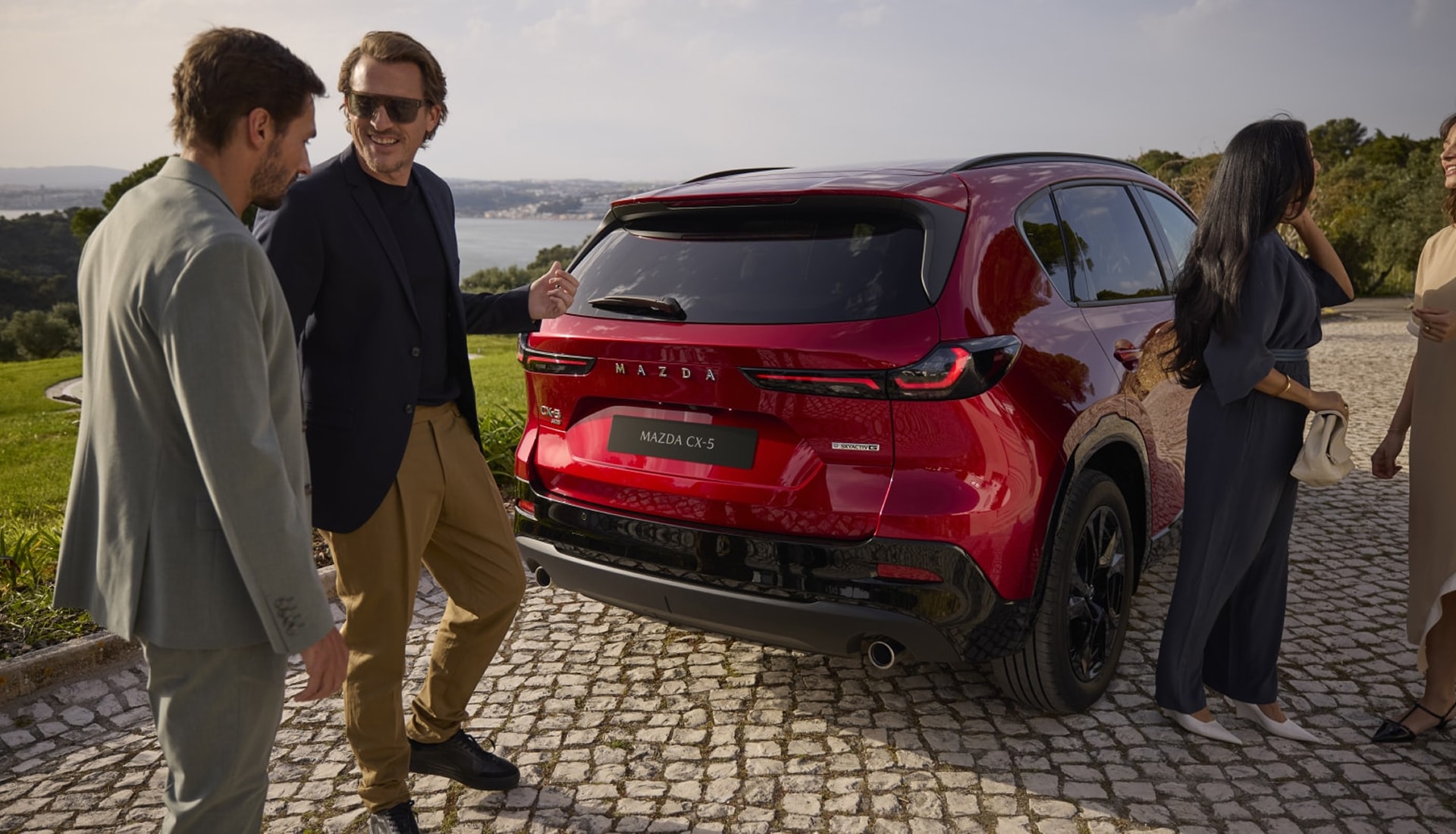 people standing near a CX-5 parked on a cobblestone driveway
