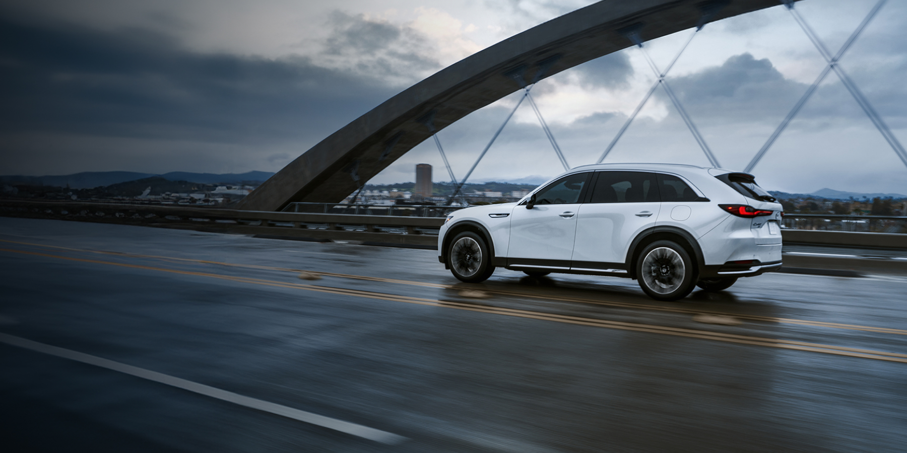 Mazda CX-90 driving on a scenic bridge