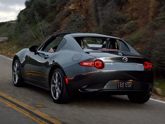 Rear shot of Miata rounding a mountain corner road