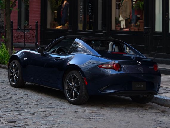 Rear shot of Miata rounding a mountain corner road