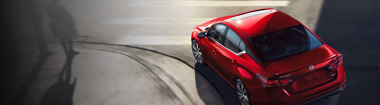 Aerial view of red Nissan Altima turning a street corner