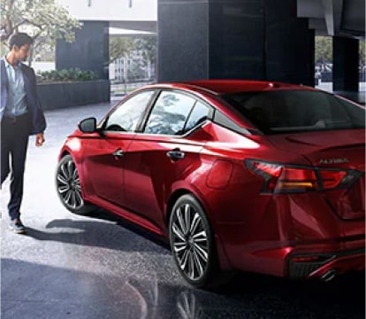 man walking next to red nissan altima outside