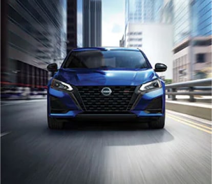 Blue nissan altima driving on a road in the city