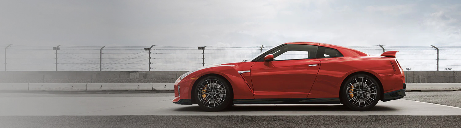 Side view of a red 2023 Nissan GT-R parked on a race track