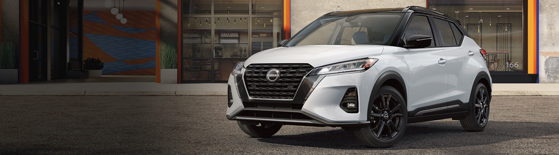 White 2023 Nissan Kicks parked in front of a restaurant