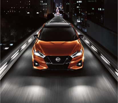 Orange Nissan Maxima driving at night