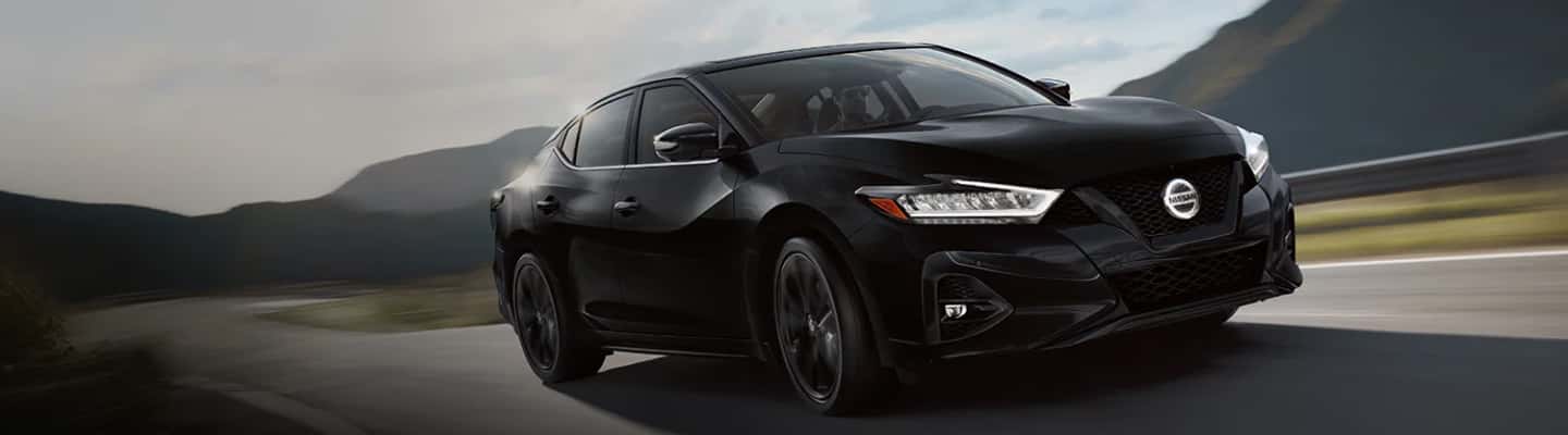 Black Nissan Maxima dring through valley