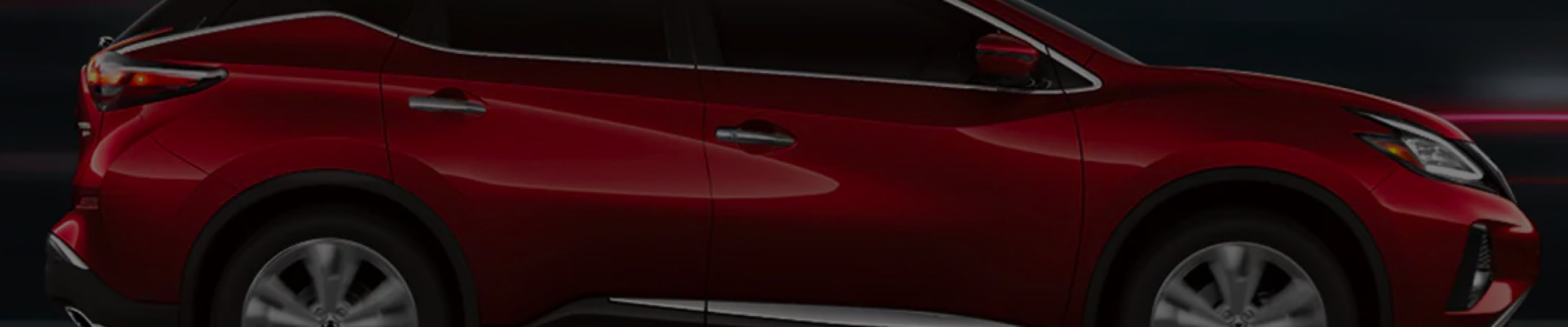 Red Nissan Murano driving through city at night