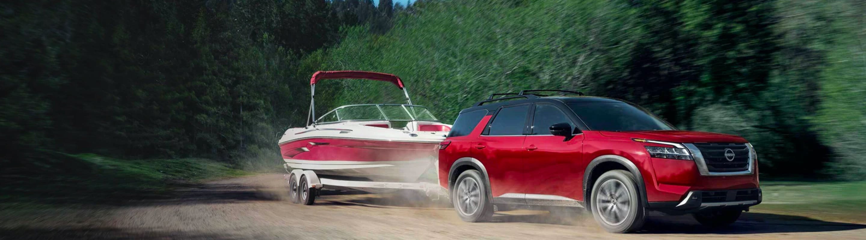 2022 Nissan Pathfinder towing a boat on a dirt road