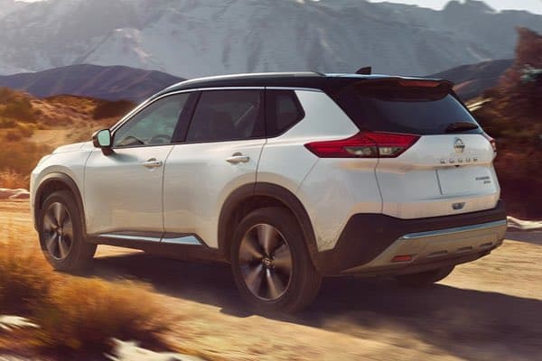 White Nissan Rogue driving on a dusty country road