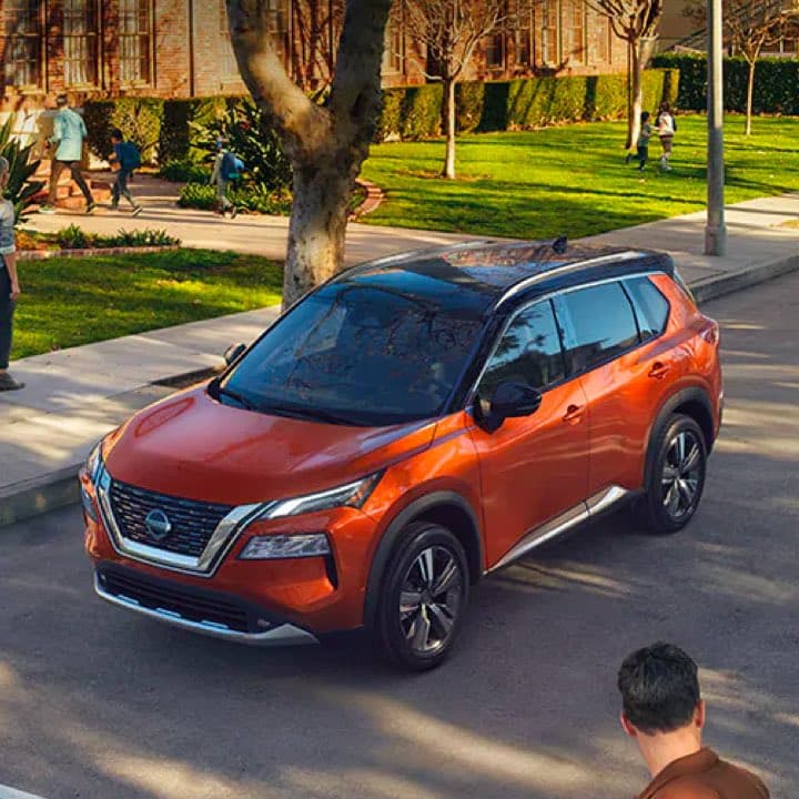 Orange Nissan Rogue driving down street