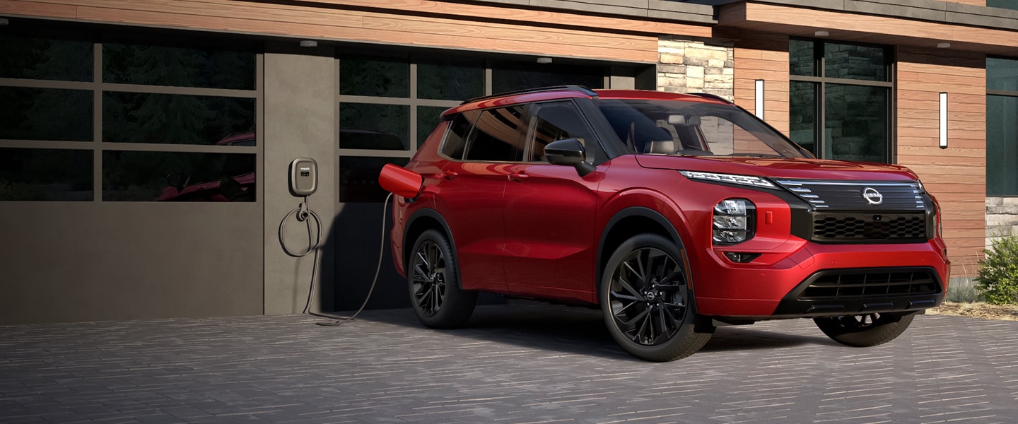 Nissan Rogue PHEV charging in front of a garage door