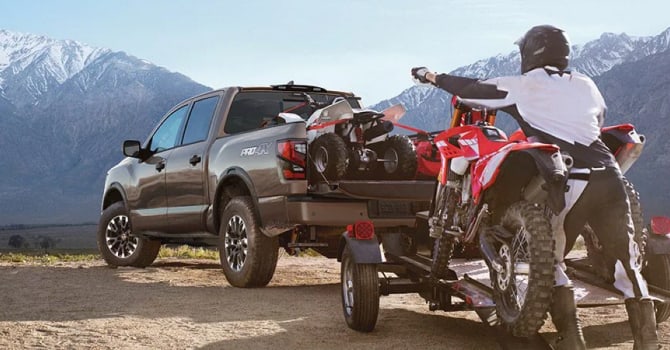 2022 Nissan Titan towing dirt bikes near mountains