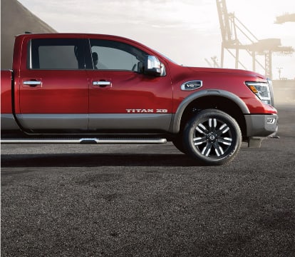 Passenger side profile view of a red 2022 Nissan Titan