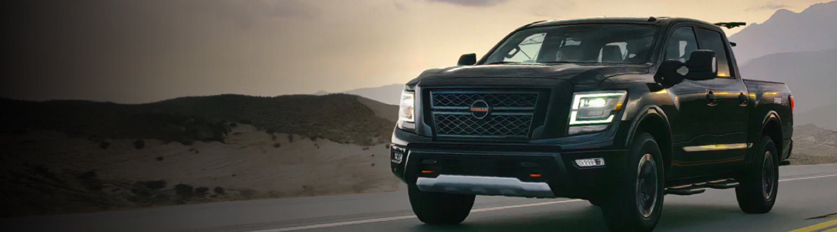 Front view of Black Nissan Titan driving down desert road