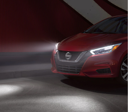Red Nissan Versa with headlights on