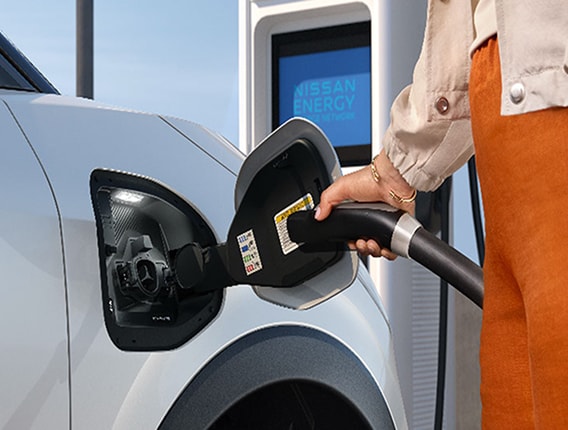 owner plugging an EV charger into a Nissan Leaf