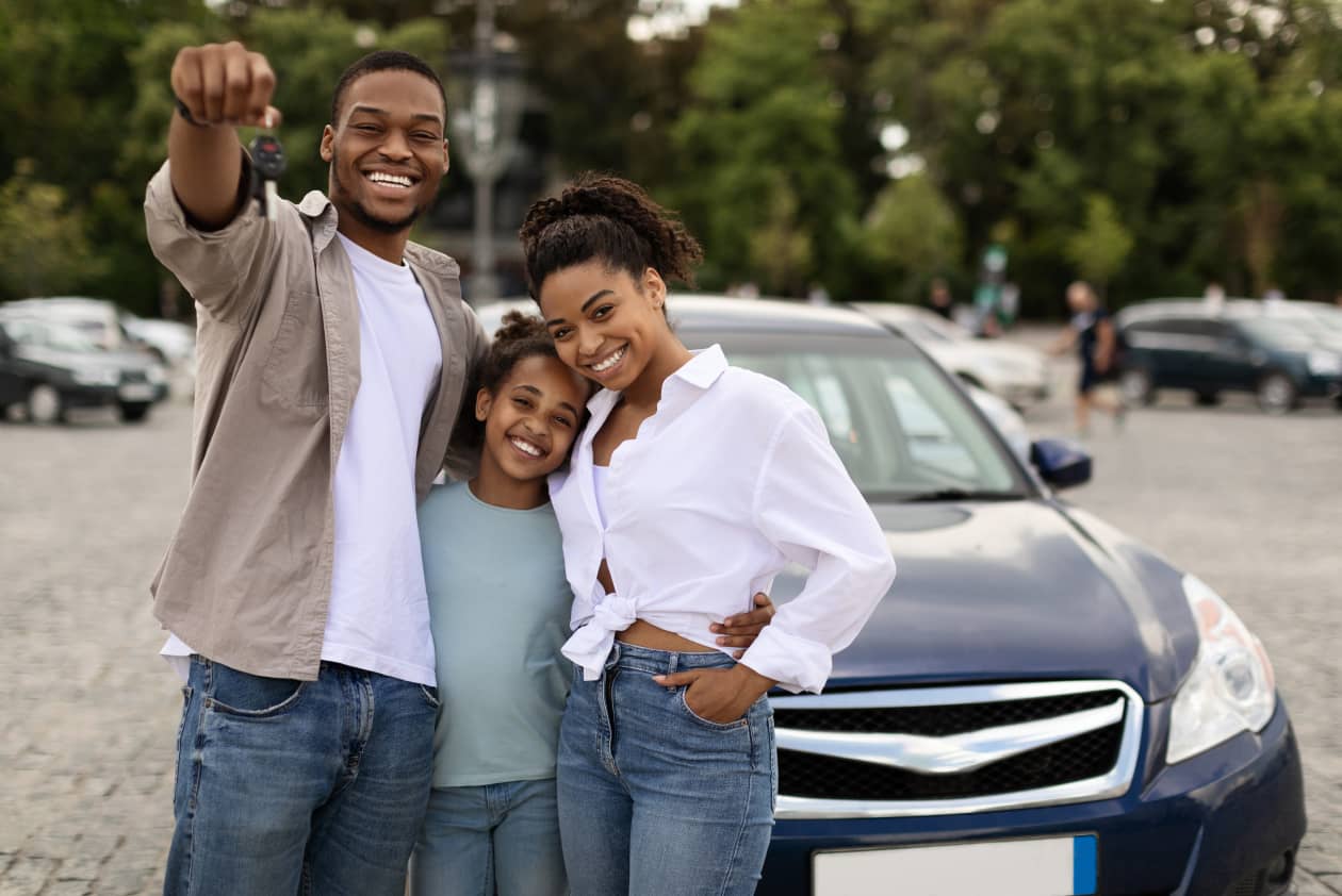 Family standing in front of a car with the dad holding out the keys
