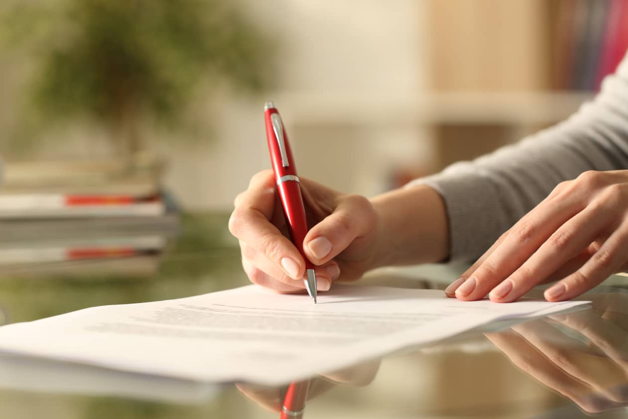 Hands holding a pen writing on paper