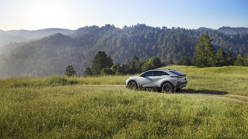A Subaru Uncharted SUV is parked on a grassy hill in the mountains.