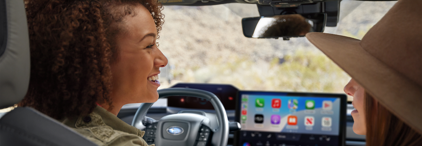 Two women talk in the front seats of a Subaru vehicle