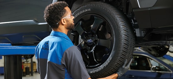 A Subaru service technician mounting a wheel