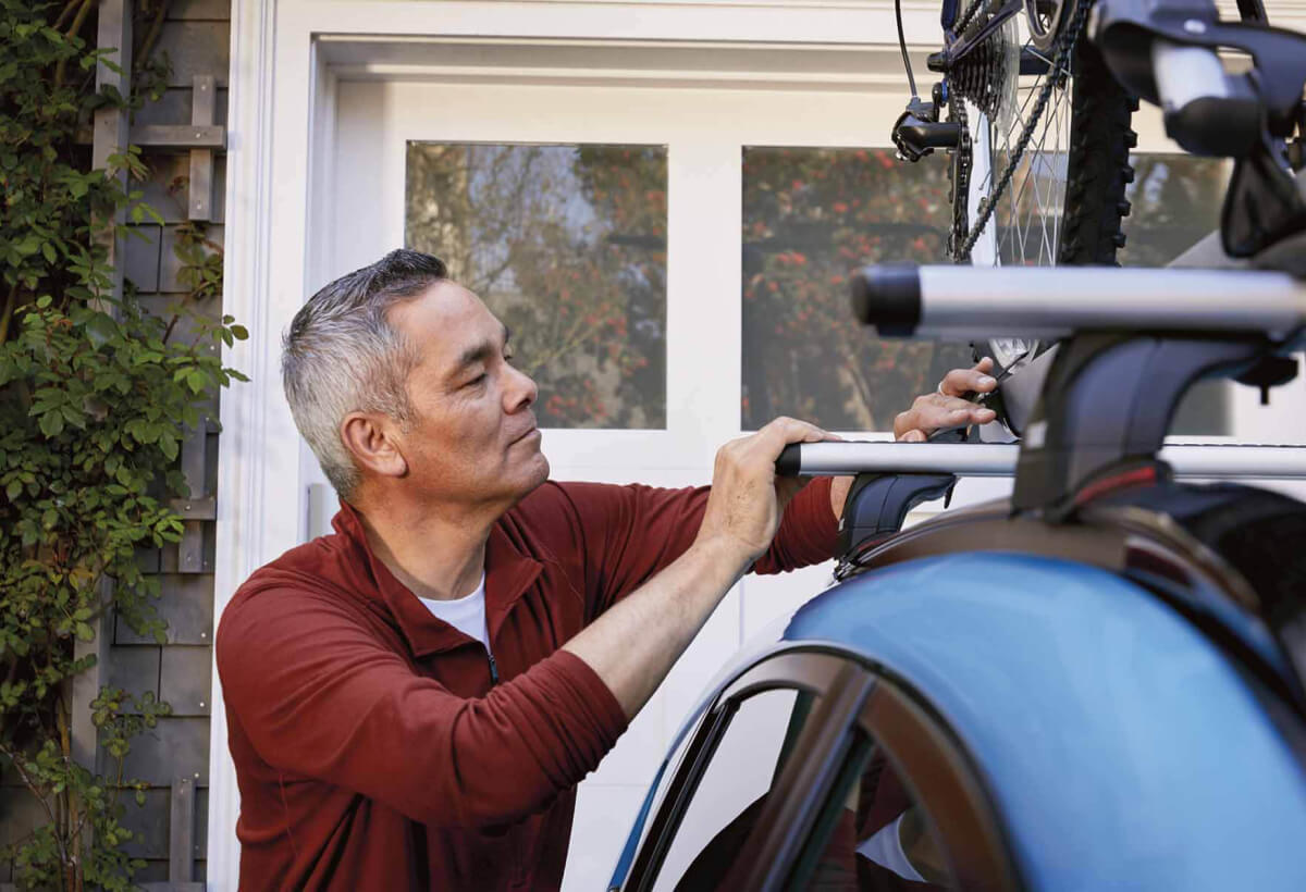 A man locking a bicycle into the Subaru Crosstrek’s roof rack