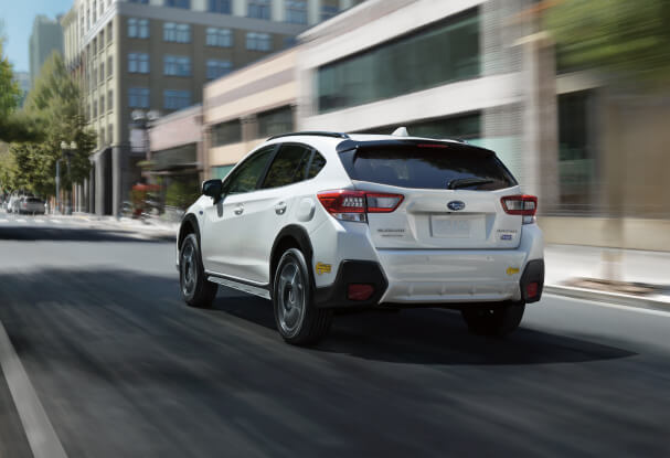 A 2023 Crosstrek Hybrid driving on a city street.